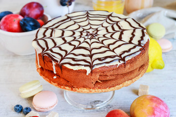 Halloween chocolate spider web cake and various fruits around.
