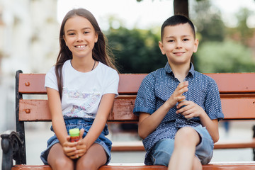 Small children blowing soap bubbles, sunny day and walking together.
