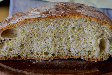 Closeup of freshly baked bread in rustic style/ Fresh round bread with a beautiful crust lies on a wooden board/ Homemade bread