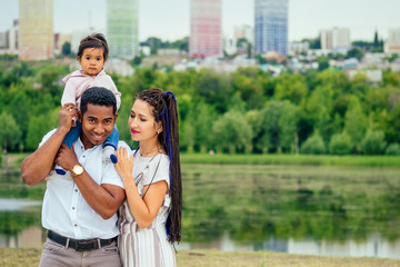 transnational interracial mother and father walking with their mixed race baby girl in autumn park