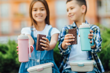 Close up photo. Thermos and sweets cake on friends hands.
