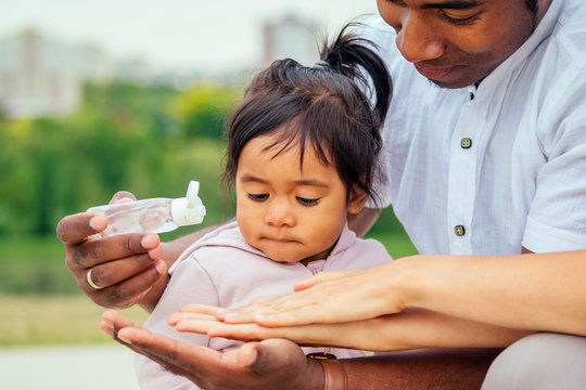 happy family applying hand-sanitizer anti-bacterial gel to daughter hands
