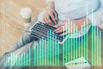 Forex graph with businessman working on computer in office on background. Concept of analysis. Double exposure.
