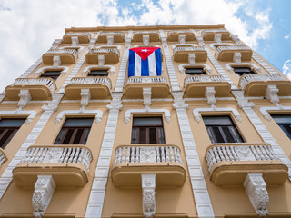 A large Cuban flag hangs from the balcony in Old Square (known in spanish as Plaza Vieja), Havana, Cuba.