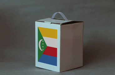 Comoros flag on white box, Paper packaging for put products. The concept of Comoros export trading.