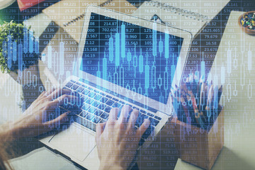 Double exposure of man's hands writing notes of stock market with forex graph background. Concept of research and trading.