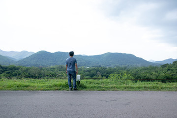 Obraz premium A man stood looking at the mountains and the sky while the wind was strong. , Evening time and the rain is coming.