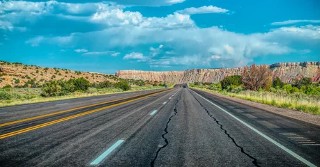 Tuinposter Arid landscape of Arizona. The crumbling sandstone mountains and the highway © konoplizkaya