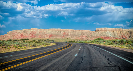 Obraz premium Arid landscape of Arizona. The crumbling sandstone mountains and the highway 