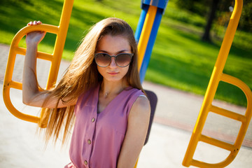 Young pretty sporty caucasian girl in a pink jumpsuit and sunglasses on the street sports field in the park on a sunny day in summer. Fitness on street sports ground.