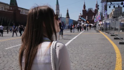 A girl walks around the square in sunny weather, a crowd of people pass by. Tourism concept