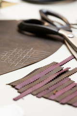 leather designers tools on a table with a scissor and leather samples