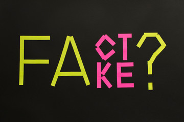 Fake News concept. The inscription FACT and FAKE on a black background.