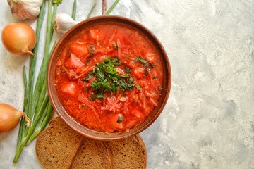Background food on the table. Ukrainian and Russian cuisine. Red borsch on a light gray background. Borsch with vegetables and tomato. Beets, onions, bread, tomato, cabbage, garlic. 
