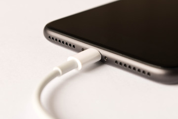 Smartphone on charge . On white background. Close up.