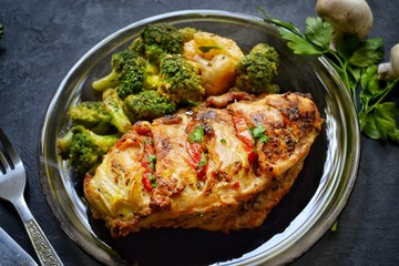 Fried chicken fillet. Broccoli and cauliflower. Baked chicken breast. Chicken and tomato. Food in a black plate on a black concrete table background.