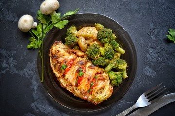 Fried chicken fillet. Broccoli and cauliflower. Baked chicken breast. Chicken and tomato. Food in a black plate on a black concrete table background.