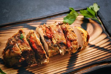 Fried chicken fillet. Baked chicken breast. Chicken and tomato on a wooden board on a black concrete table background.