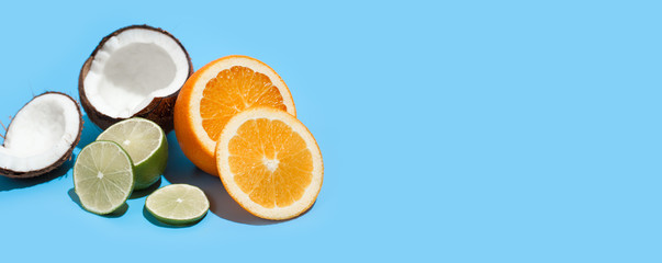 Fresh juicy orange, coconut and green lime isolated on blue background. Concept of Healthy eating and dieting. Travel and holiday concept. Copy space. Free space for your text