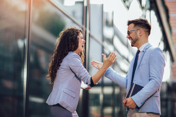 Smiling business colleagues greeting each other outdoors - obrazy, fototapety, plakaty