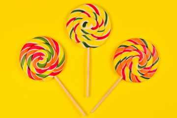 Colorful candy on a yellow  background. Lollipop. Top view. Copy space.