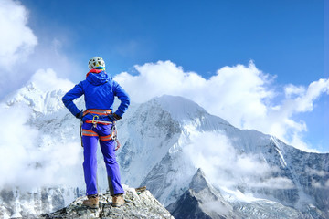 Climber reaches the summit of mountain peak enjoying the landscape view.