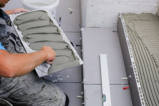 Tiler hands working on a new house entrance, local and professional handyman applying tiles to the steps.