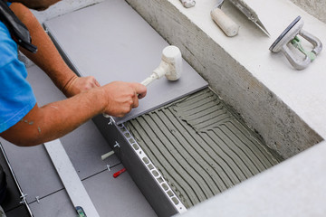 Tiler hands working on a new house entrance, local and professional handyman applying tiles to the steps.