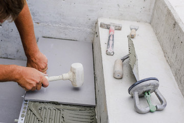 Tiler hands working on a new house entrance, local and professional handyman applying tiles to the steps.