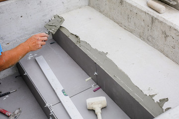 Tiler hands working on a new house entrance, local and professional handyman applying tiles to the steps.