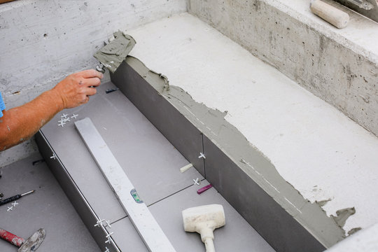 Tiler hands working on a new house entrance, local and professional handyman applying tiles to the steps.