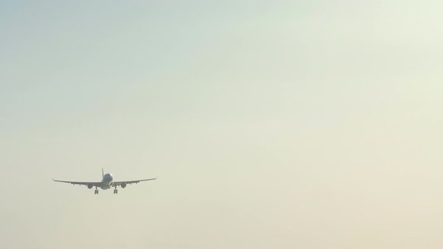 Close up shot of huge civil jet aircraft is landing in airport in sunset with heavy wind