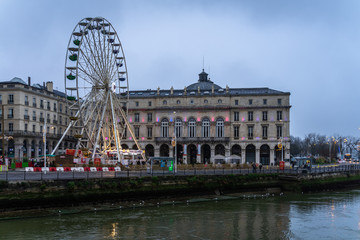 Fototapeta na wymiar Bayonne city hall and Ferris wheel on the banks of Nive river, France.