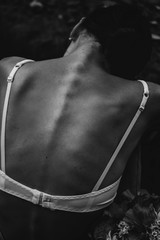 Fototapeta na wymiar Woman back, bra straps for breast cancer concept. Dark style. White bra, skinny young woman