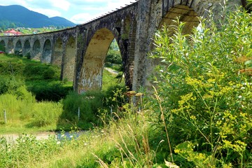  Old viaduct bridge on a background of mountains and green grass