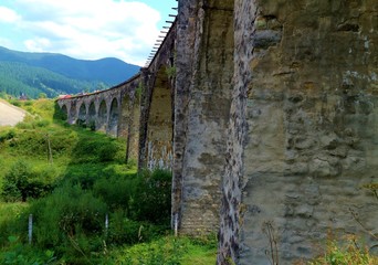  Old viaduct bridge on a background of mountains and green grass