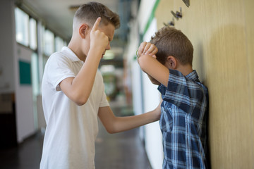 Boy bully   Bullying  classmate in school hallway. 
