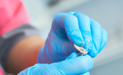 Fototapeta premium Close-up hands of young woman doctor anesthesiologist dressed in pink gown, blue gloves prepares solution for anesthesia in the operating room before the surgery.