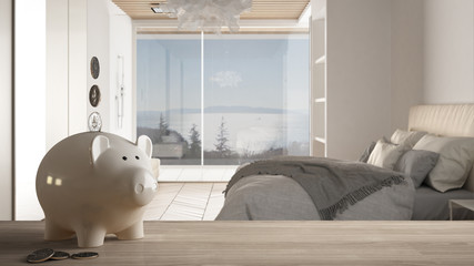 Wooden table top or shelf with white piggy bank with coins, modern panoramic bedroom with shower and bed, expensive home interior design, renovation restructuring concept architecture