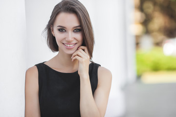 Beautiful elegant woman outdoors. Lady in black dress. Young female classic portrait.