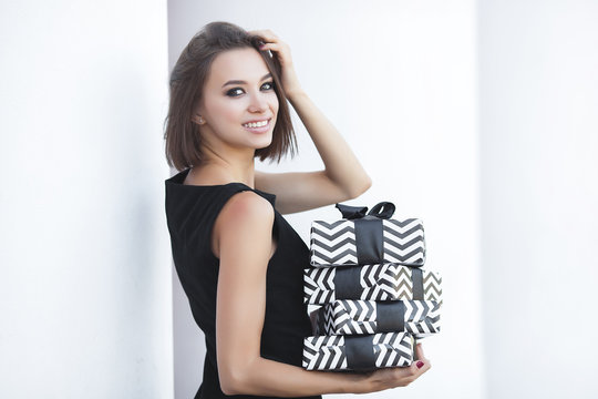 Young attractive woman holding present boxes and smiling. Beautiful woman with black presents.