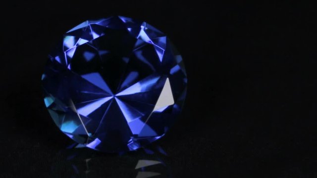 Slider shot, large blue rhinestone on a black background. Beautiful light reflection.