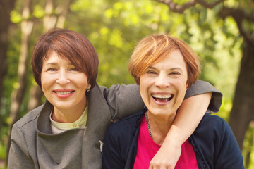 Two happy women walking in summer park, portrait