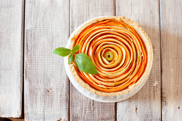 Homemade vegetable tart with cabbage and carrot decorated with basil on old wooden table