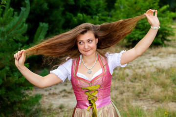 young woman in dirndl playing with her hair and making grimace