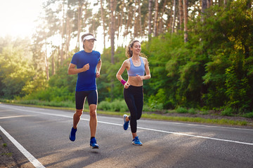 Caucasian female sports woman and fit man in full body length running pine forest road. healthy lifestyle concept