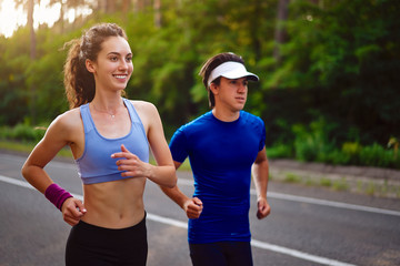 Caucasian female sports woman and fit man in full body length running pine forest road. healthy lifestyle concept