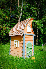 Fototapeta na wymiar A wooden fairy-tale toy house in green grass in the sun. The concept of 