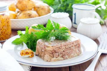 Homemade Aspic of turkey meat on a white plate with boiled potatoes, horizontal