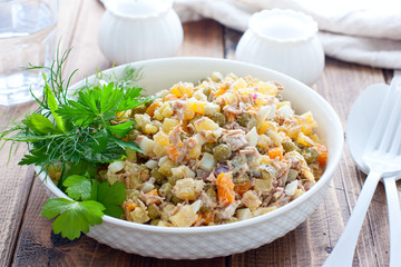 Olivier salad with boiled meat and meat on a wooden table, horizontal